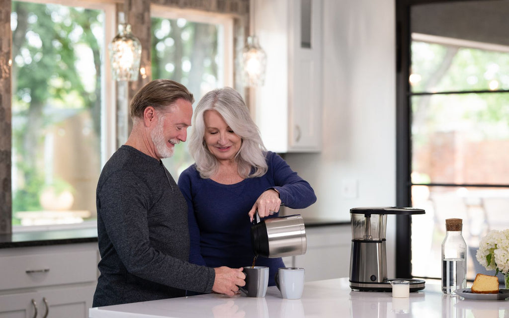 Man and woman are pouring brewed coffee into their mugs.