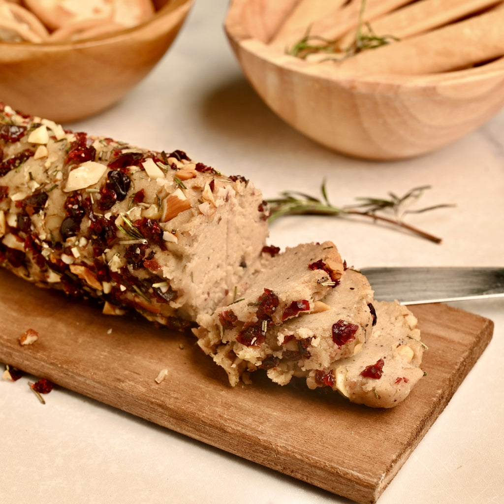 A cashew cheese log on a wooden cutting board