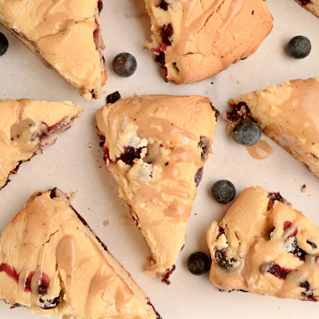 White background with triangular cut blueberry scones scattered across it