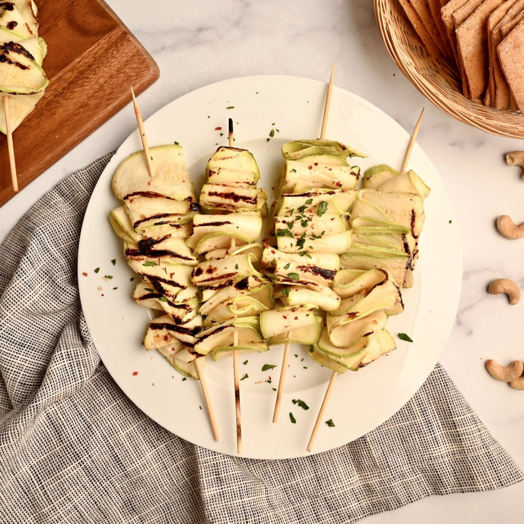 A white plate with skewers covered in zucchini ribbons