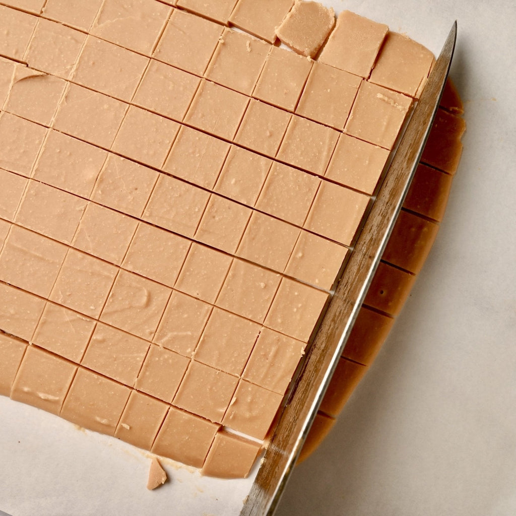 A block of peanut squares being cut with a knife