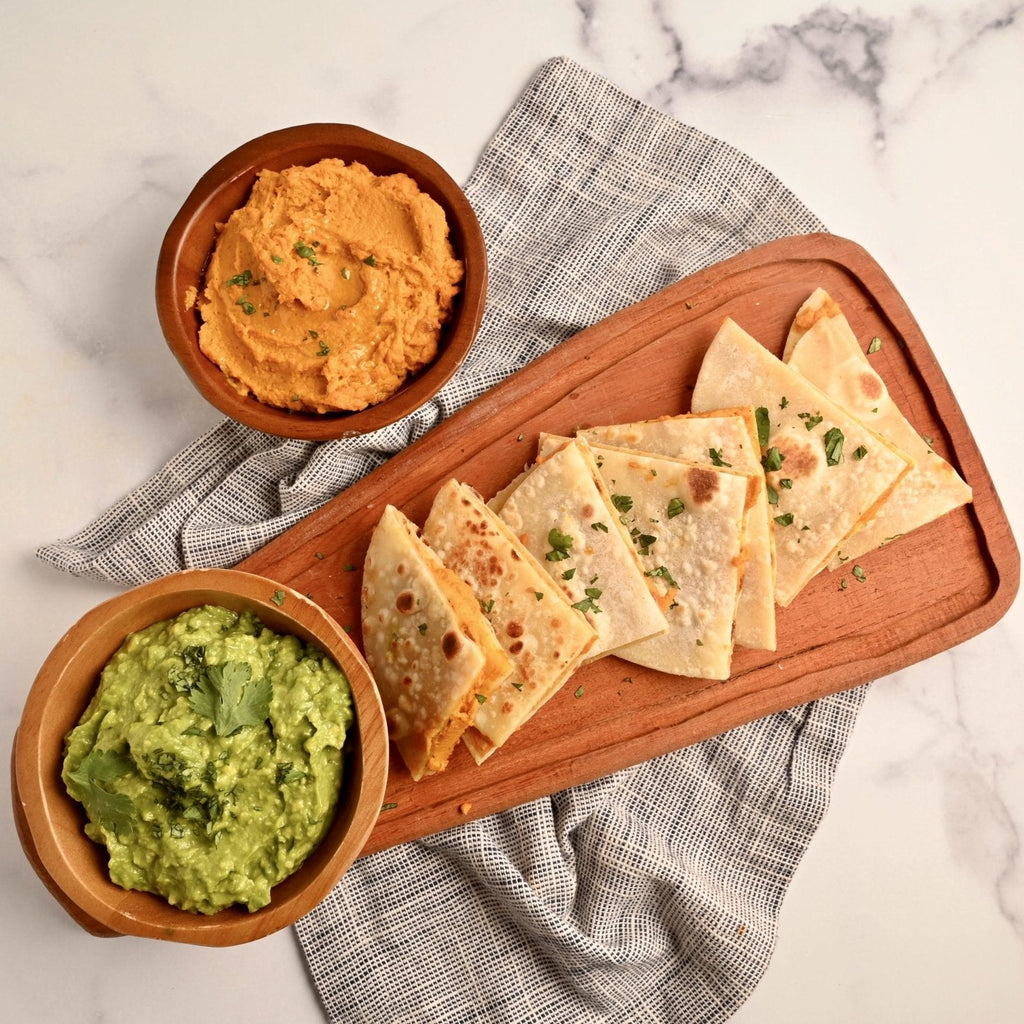 Tray of homemade plant-based quesadillas with a bowl of roasted carrot hummus
