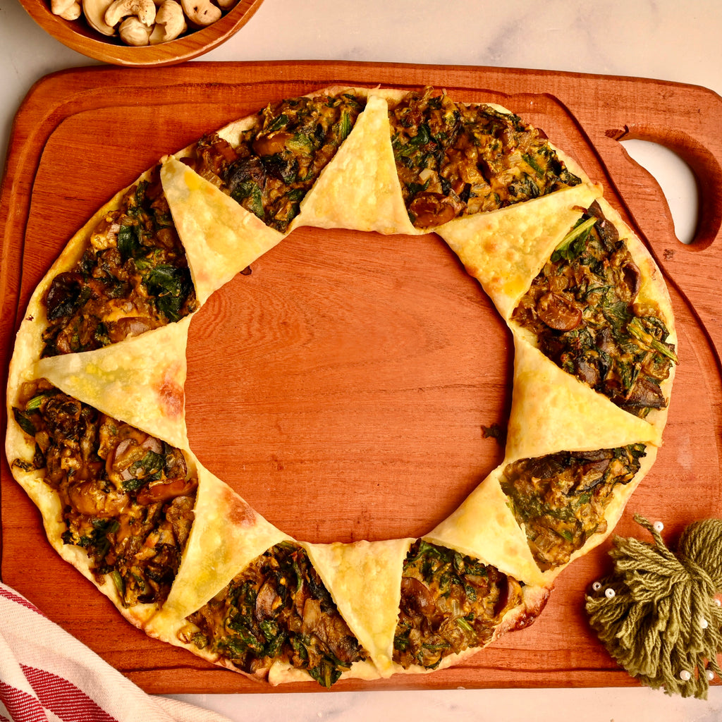 A mushroom and spinach pizza ring on a wooden serving board