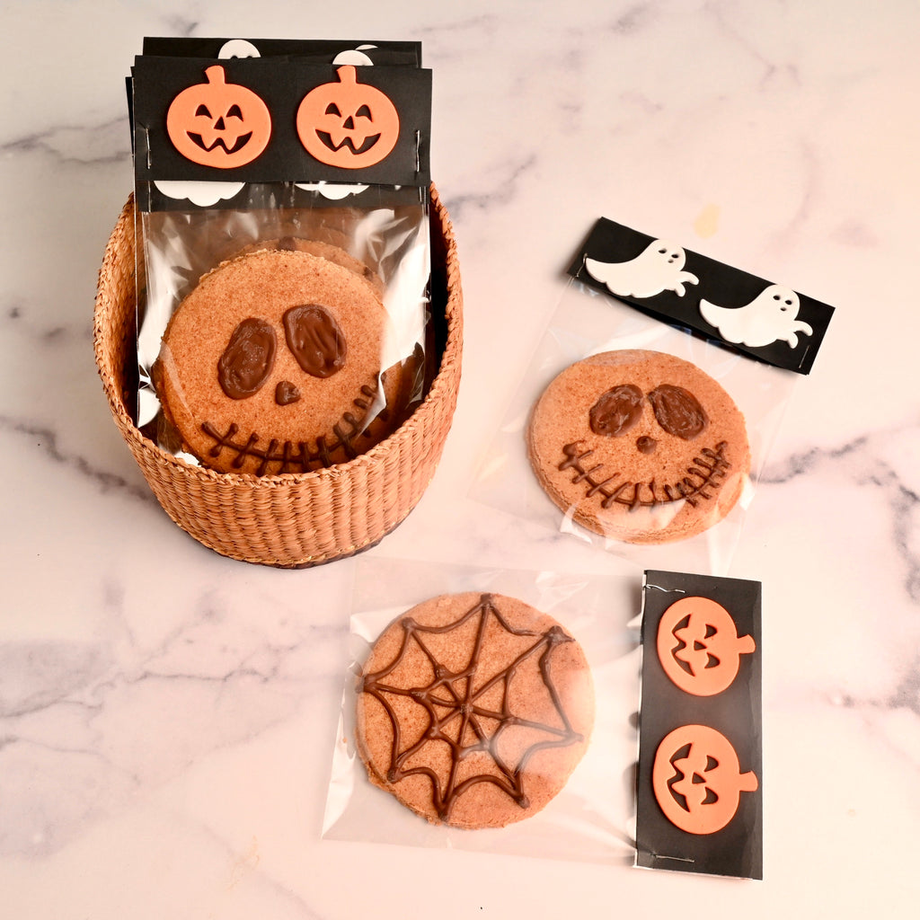 Cookies with Halloween faces on them wrapped in Halloween plastic