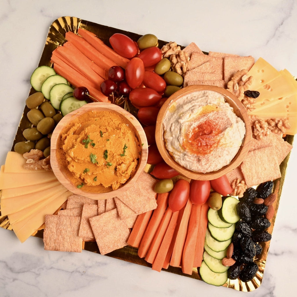 A platter full of cheese, crackers, veggies, and two bowls of homemade dips