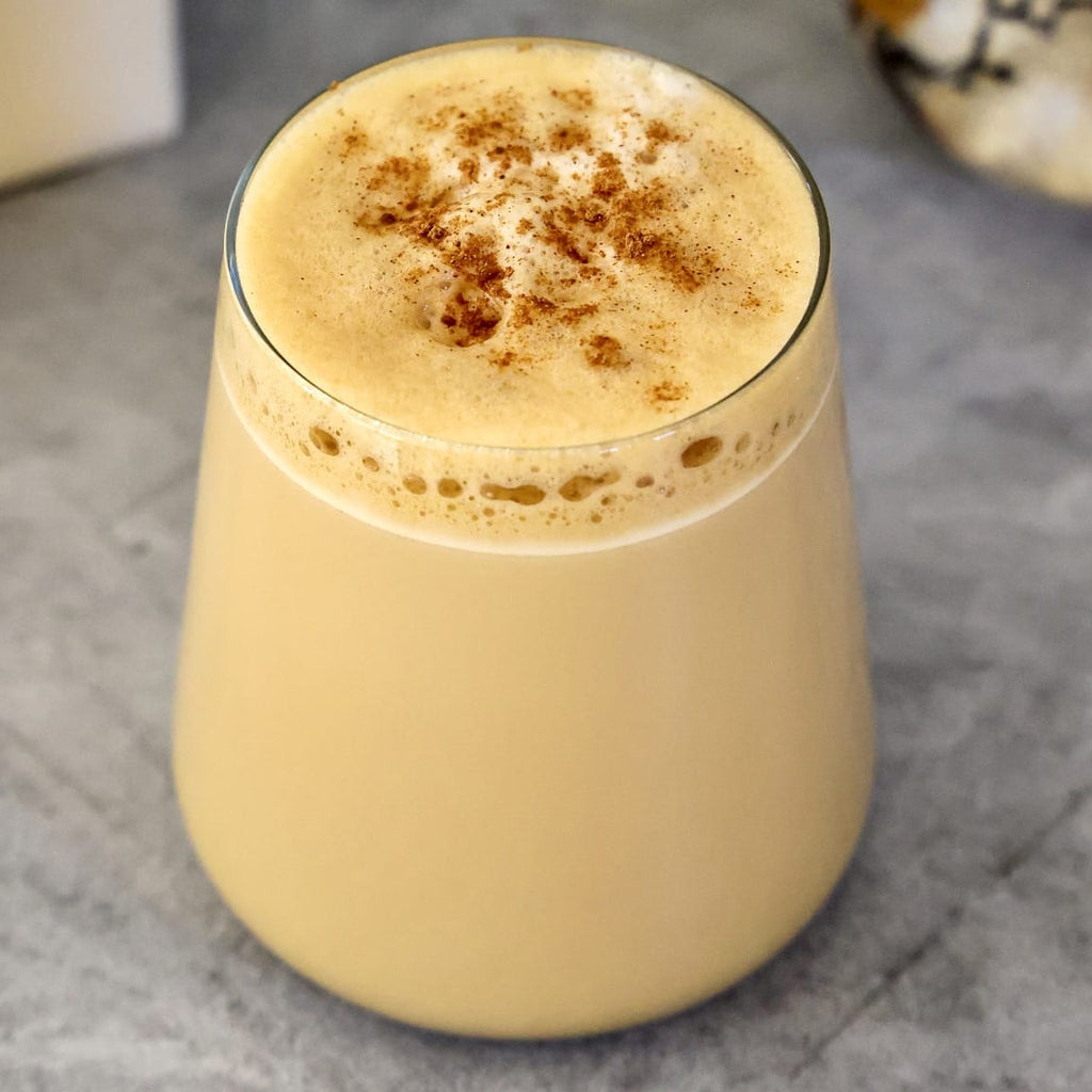 Clear glass is filled with a pumpkin spiced latte with a dash of cinnamon on top