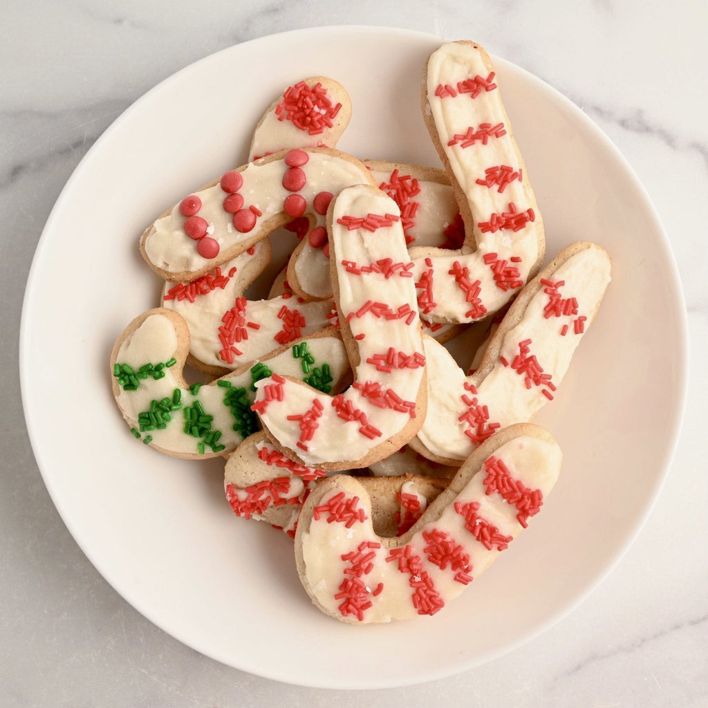A white plate with sugar cookie cookies in the shape of candy canes