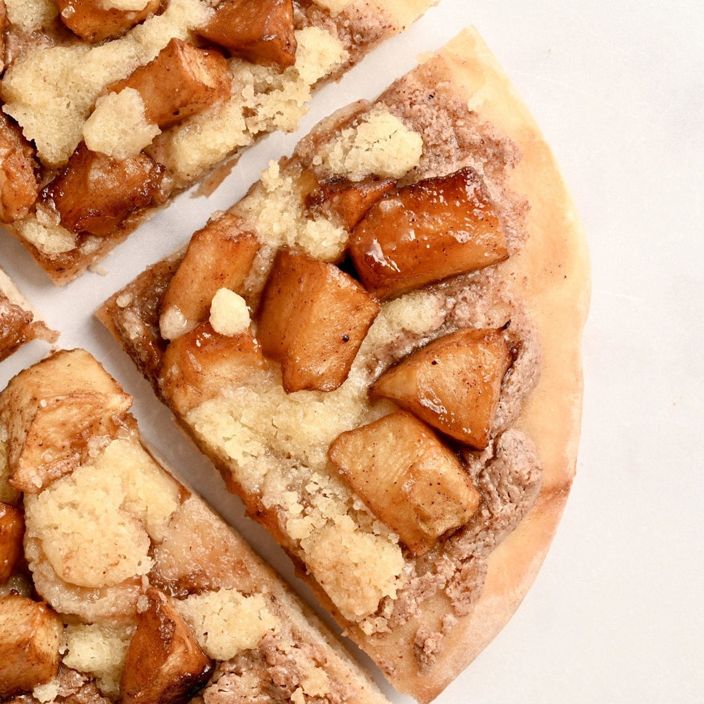 Close up of a slice of apple streusel breakfast pizza with chunks of apples on top with a homemade almond butter crumble covering the top of the apples