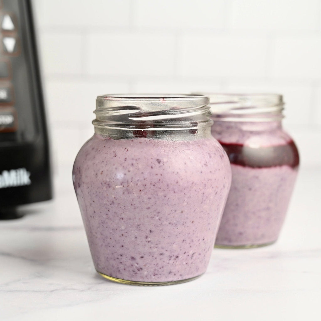 Two glass jars filled with bright blue and purple blueberry yogurt