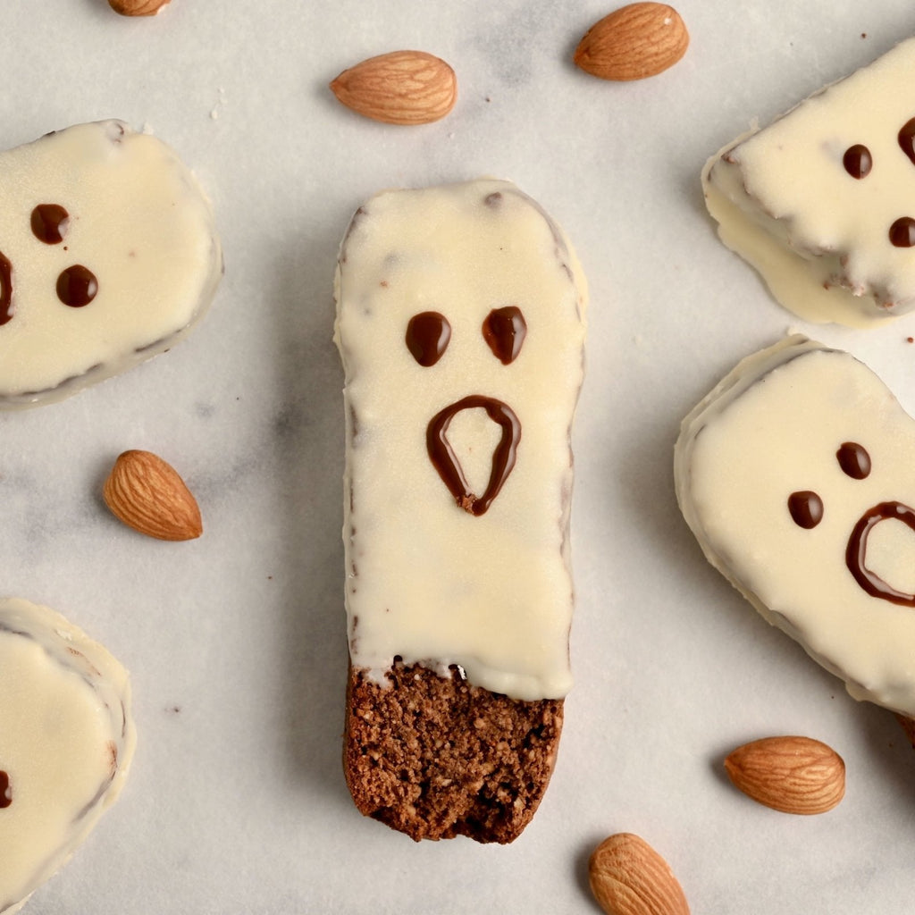 Biscotti covered in white chocolate with a ghost face in brown icing