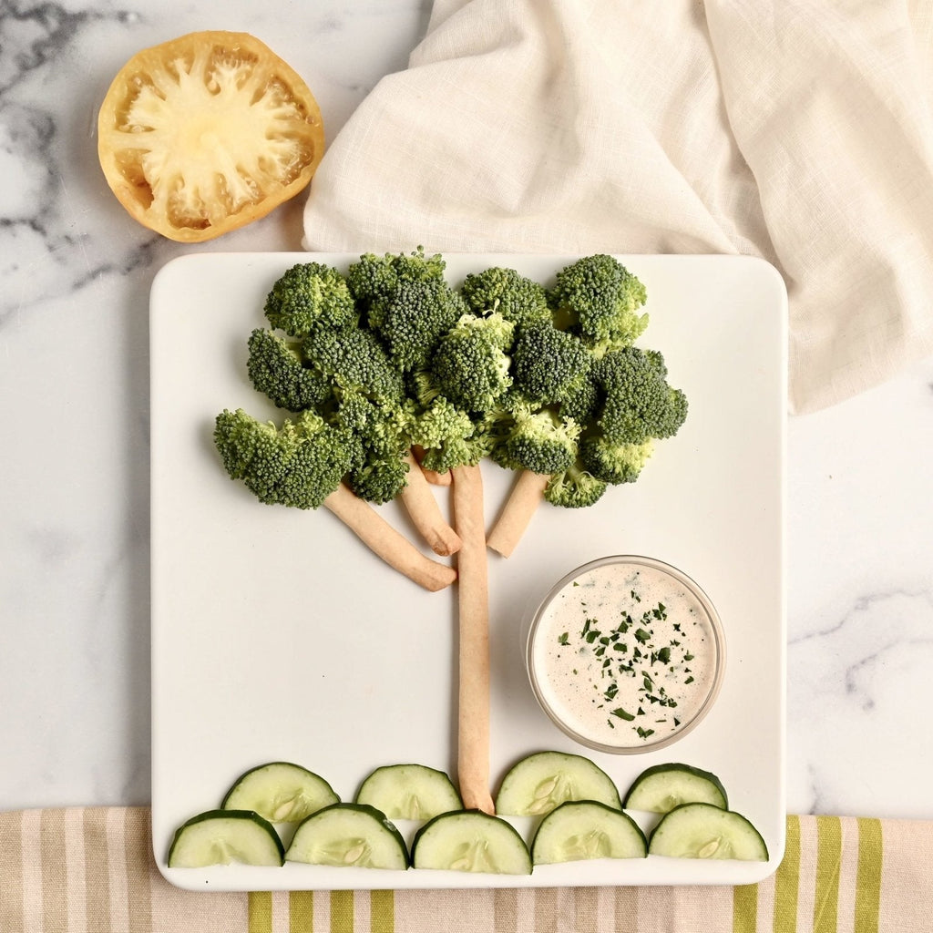 White plate with vegetables placed in the shape of a tree with dipping sauce