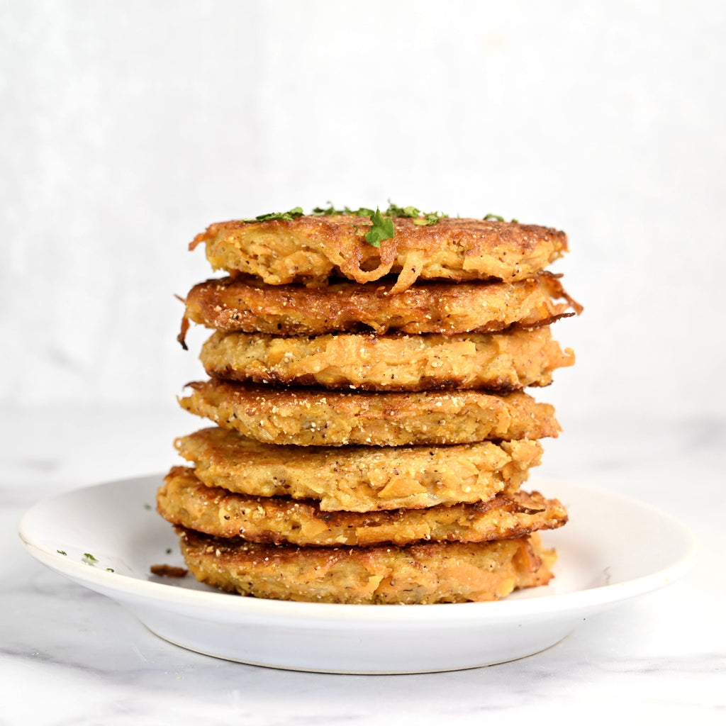 A white plate stacked with a tower of butternut squash fritters
