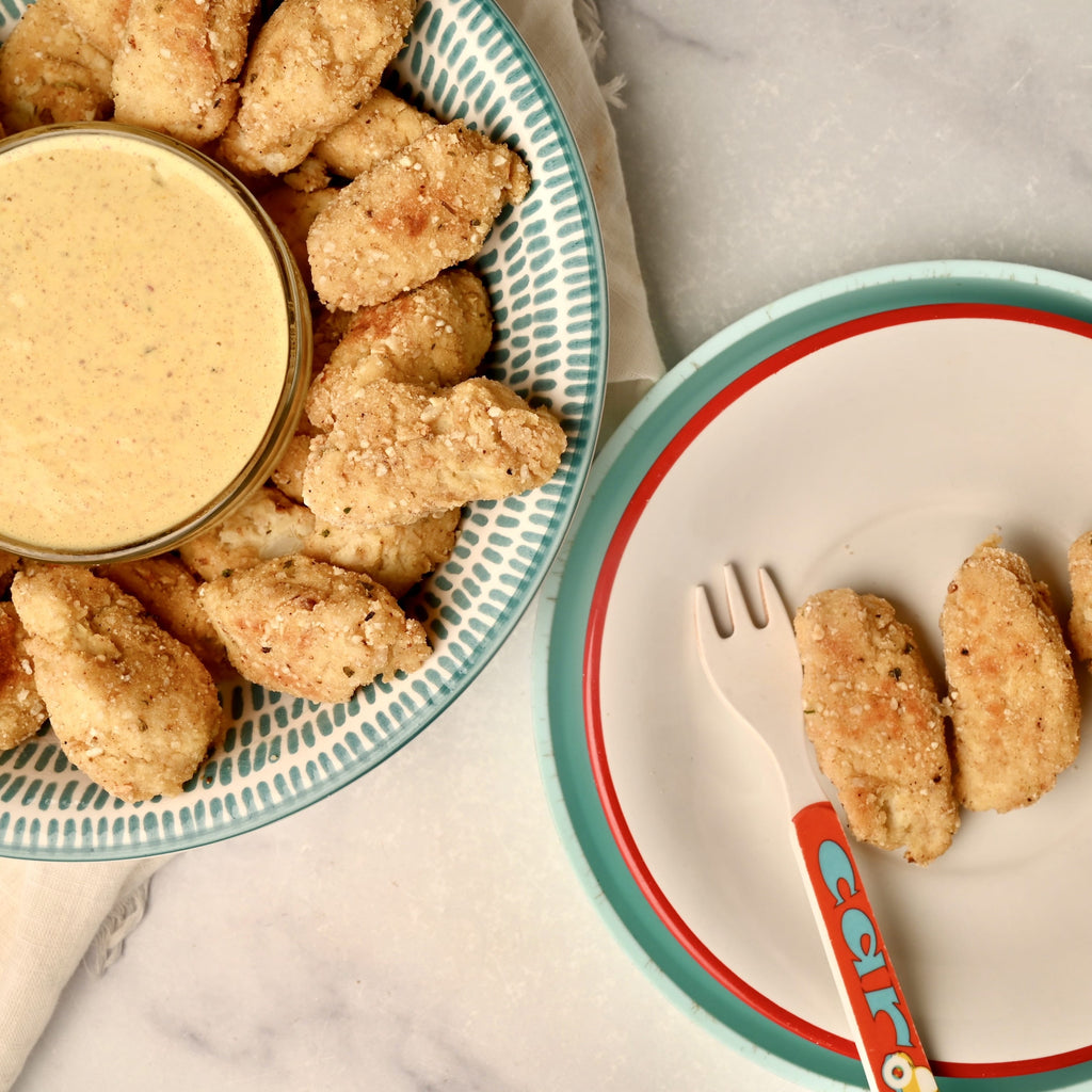 A plate of homemade cauliflower tots with a small bowl of dipping sauce