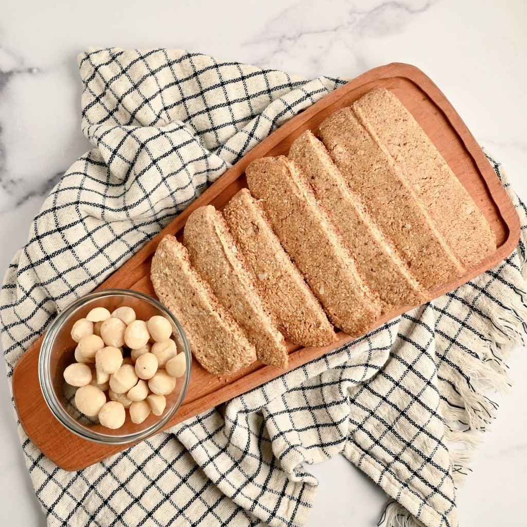 A kitchen towel with a wood serving platter on top covered in homemade biscotti slices