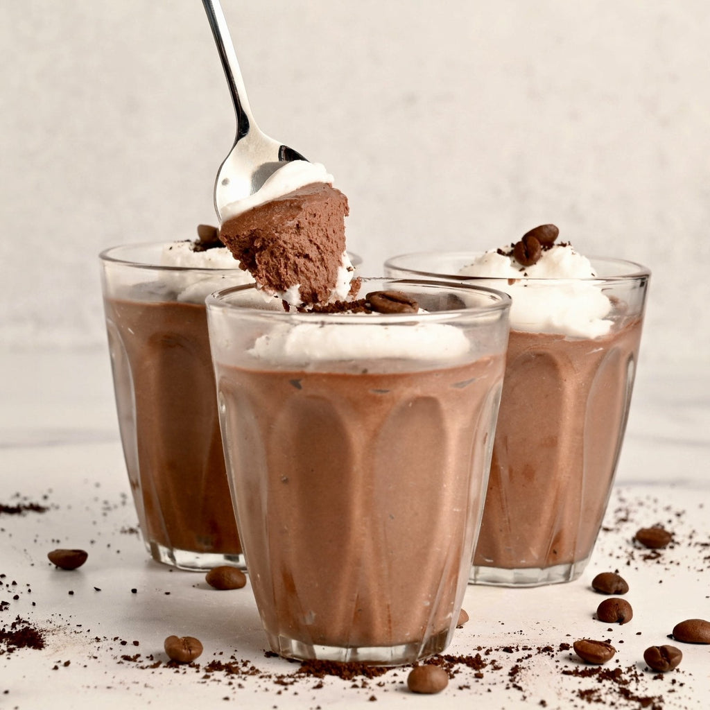 Three clear glass cups filled with homemade chocolate mousse and topped with a dollop of whipped cream