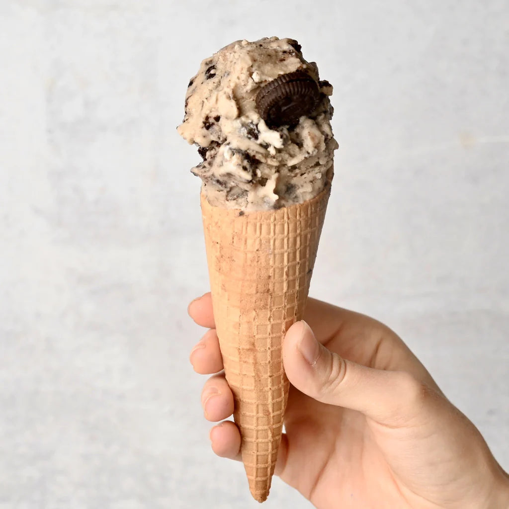 An ice cream cone with a scoop of cookies and cream nice cream
