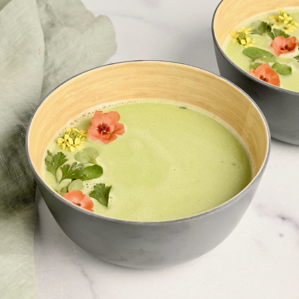 Bowl filled with light green chilled gazpacho with florals on top