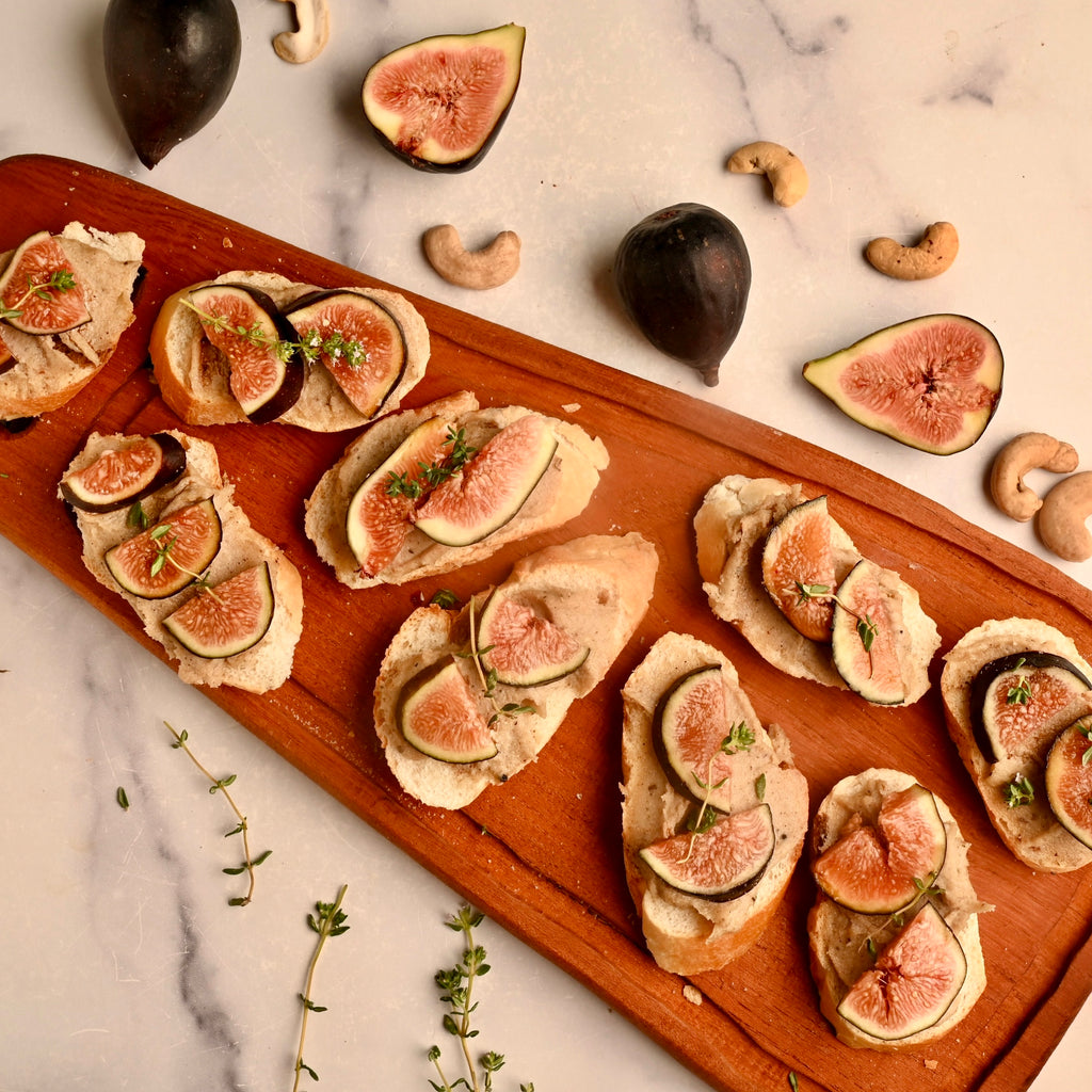 A wooden cutting board with fig bruschetta pieces all over it