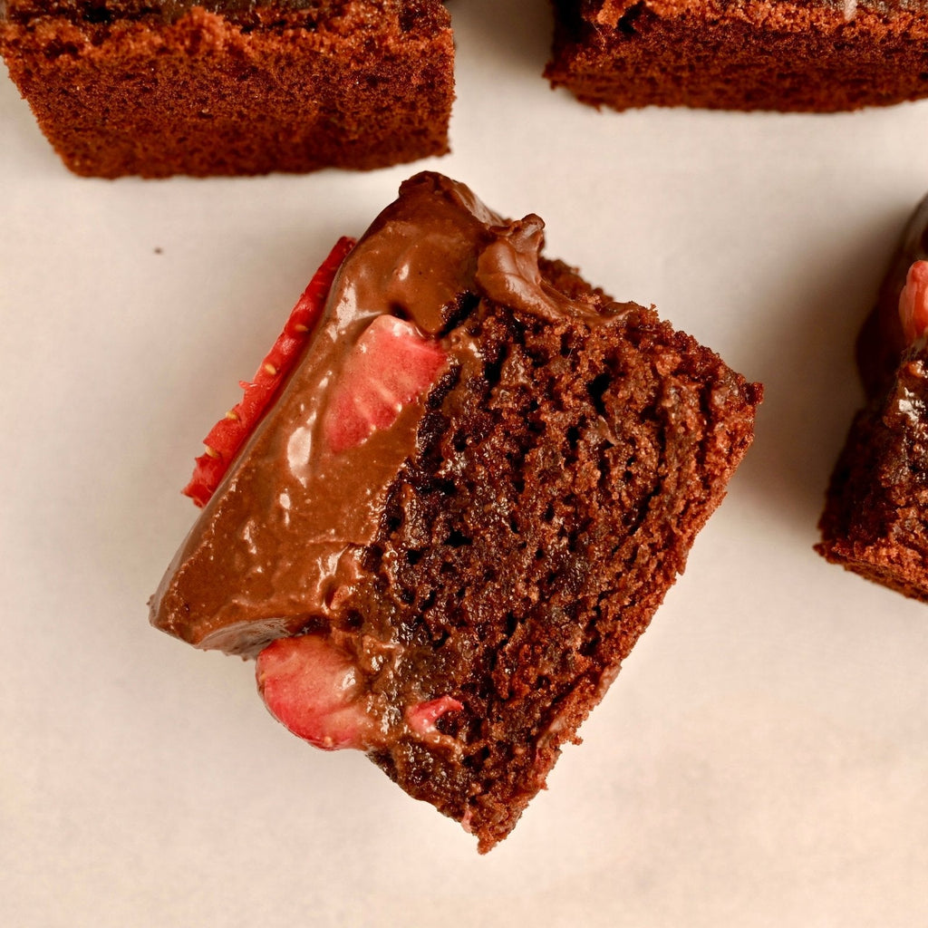 A chocolate brownie with chocolate frosting and fresh strawberry slices