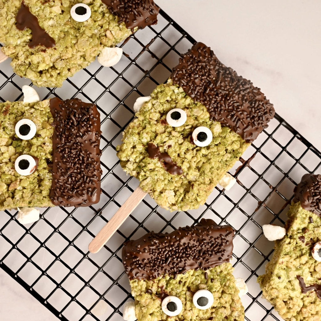 Green Frankenstein face rice crispy treats laying on a black cooling rack