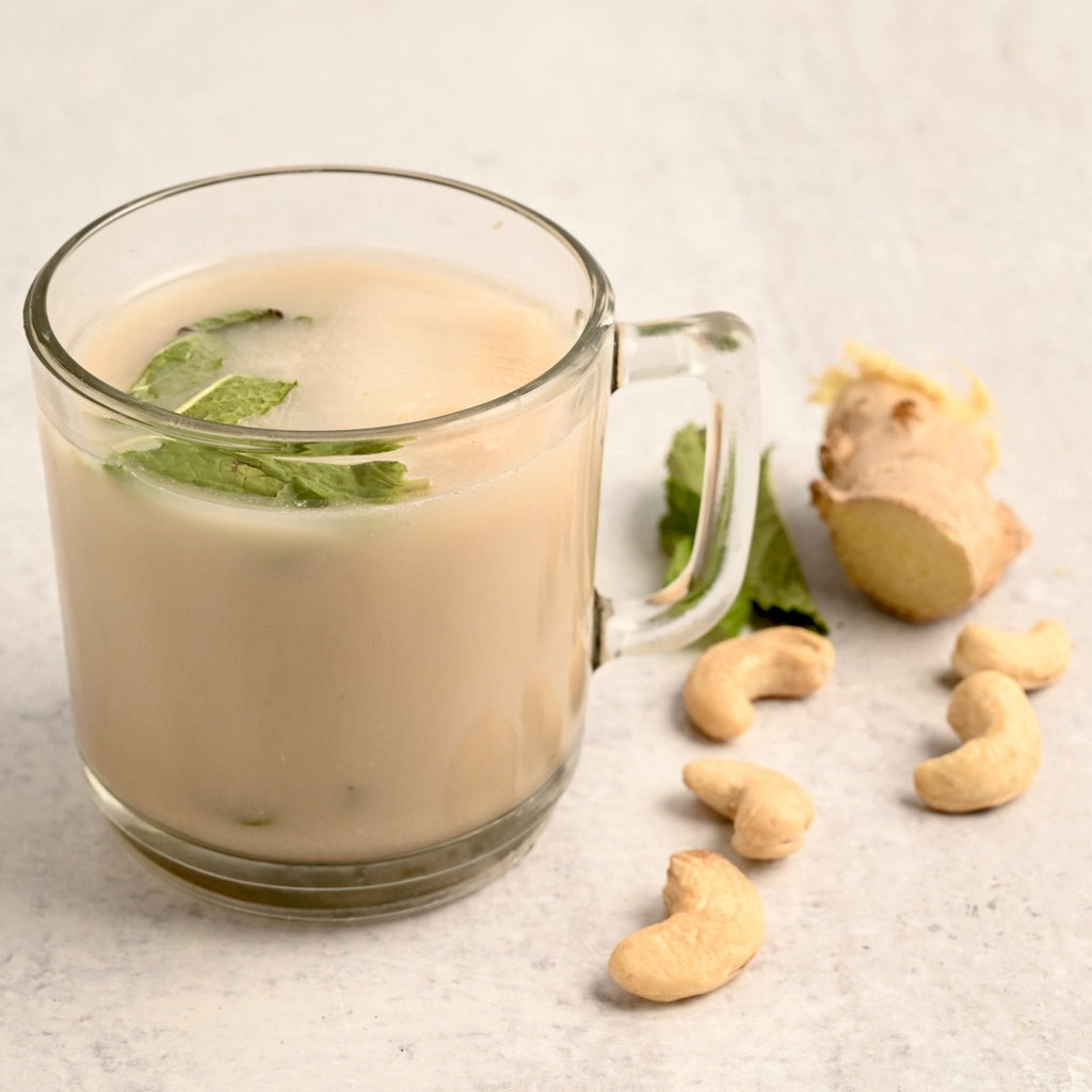 A glass coffee mug filled with ginger mint tea with fresh mint leaves floating on top