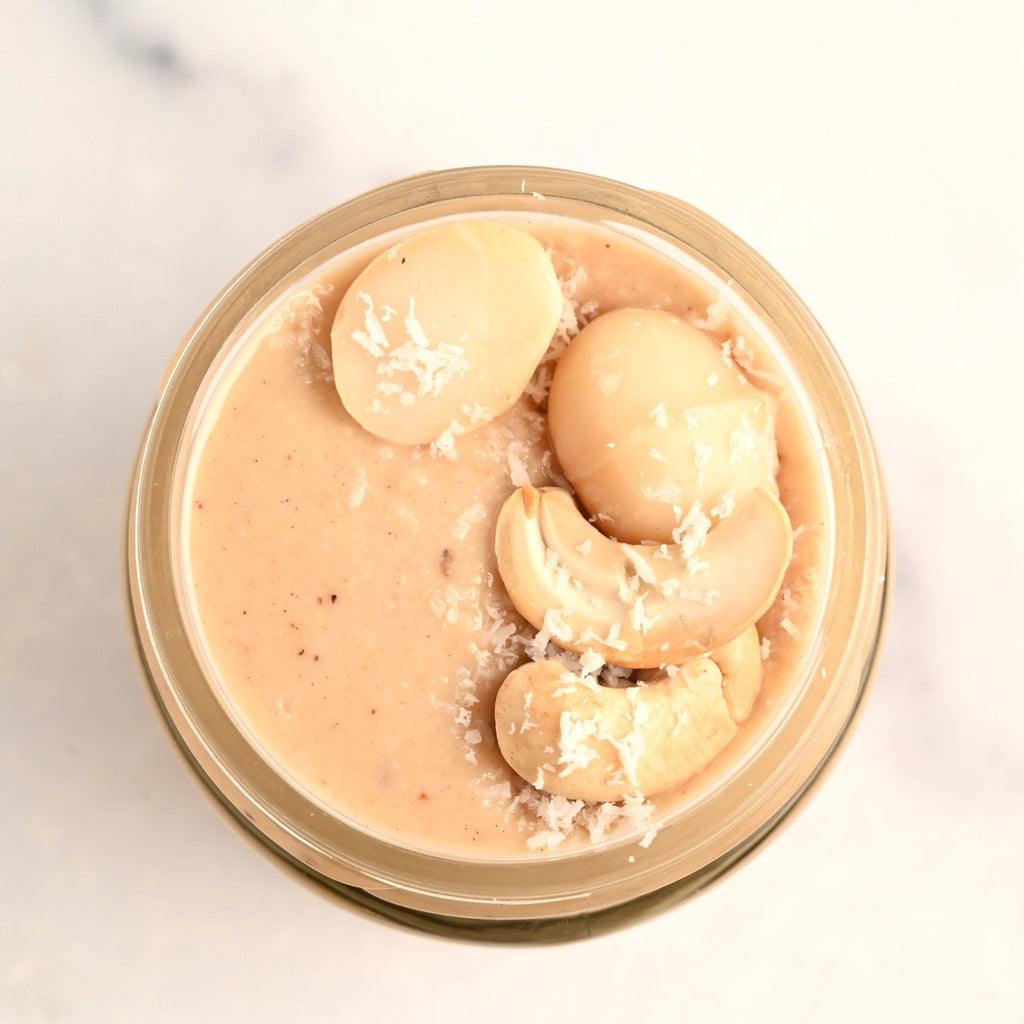A clear glass jar filled with macadamia nut butter with cashews and macadamia nuts on top