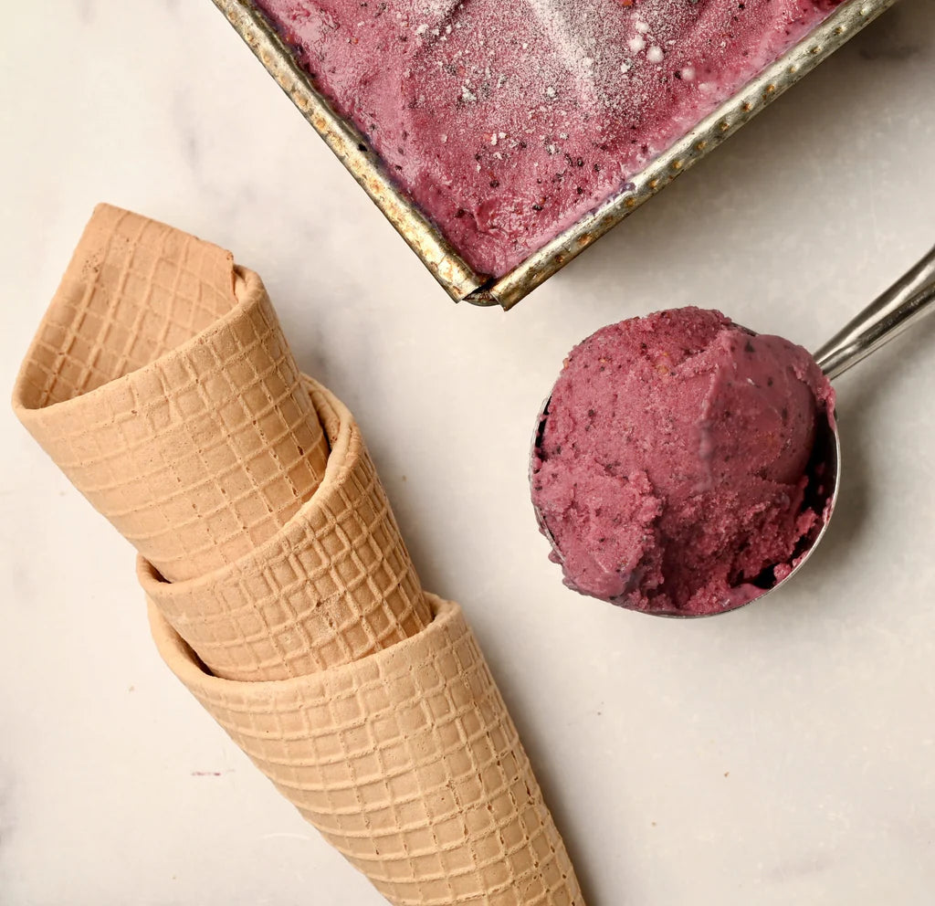 Purple berry ice cream with an ice cream cone and stacked ice cream cones