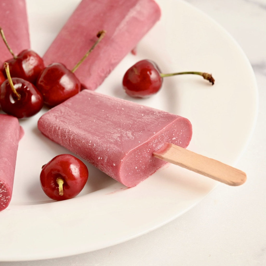 White ceramic plate with cherry popsicles and fresh cherries