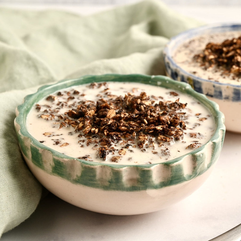 A white ceramic bowl with homemade granola inside topped with chocolate shavings