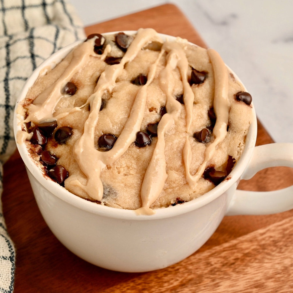 A white ceramic coffee mug filled with homemade chocolate chip cookie dough