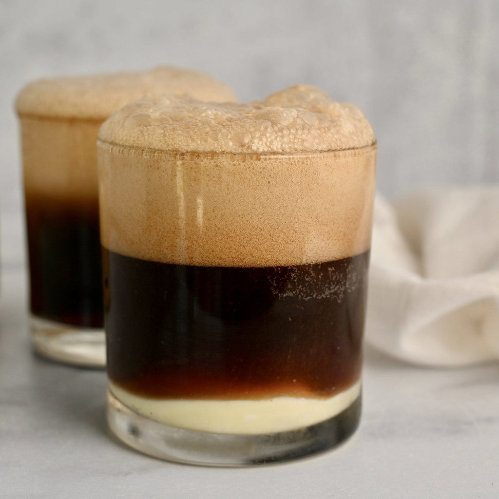 Two short glasses filled with peanut butter root beer float