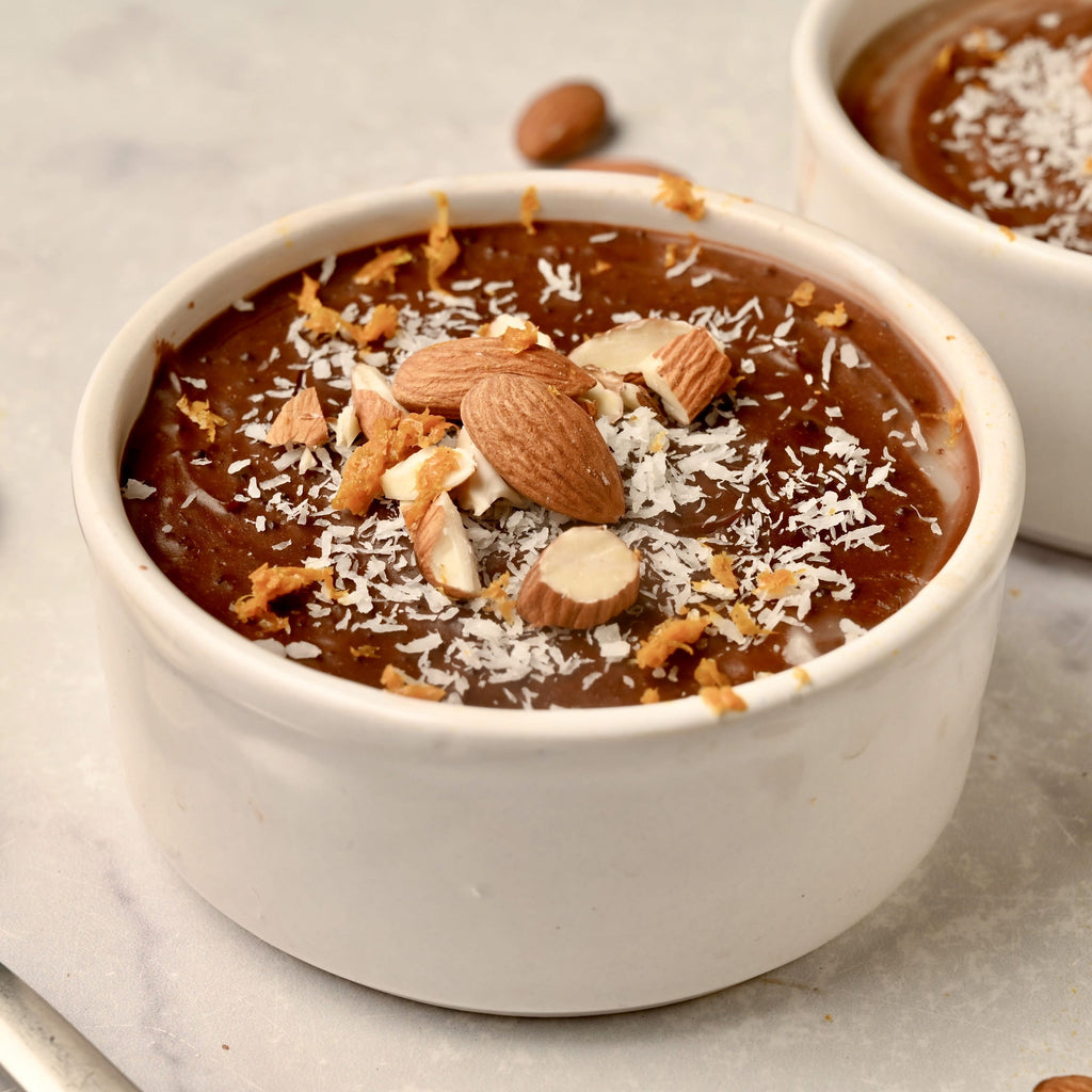 White ceramic bowl filled with chocolate and vanilla custard and topped with almonds and coconut flakes