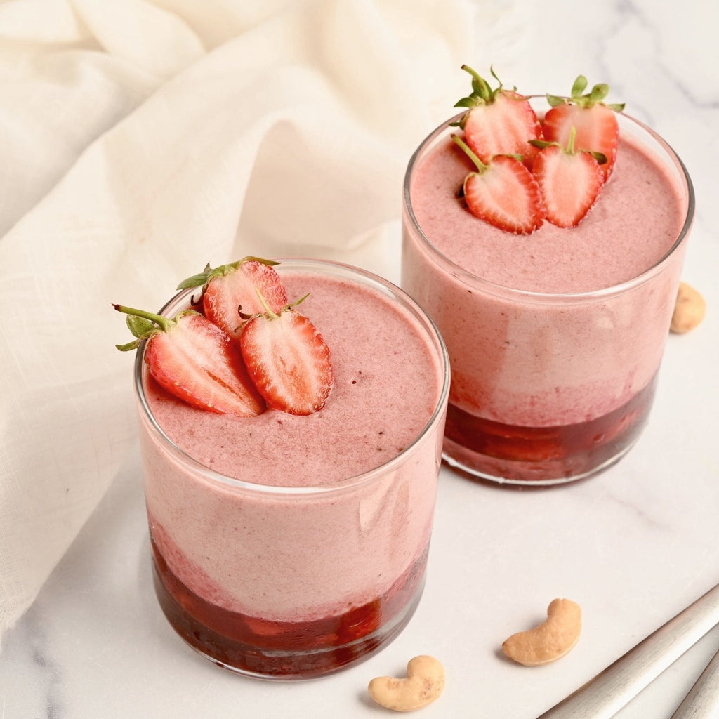 Two small glasses filled with homemade strawberry mousse and each is topped with a few slices of fresh strawberries
