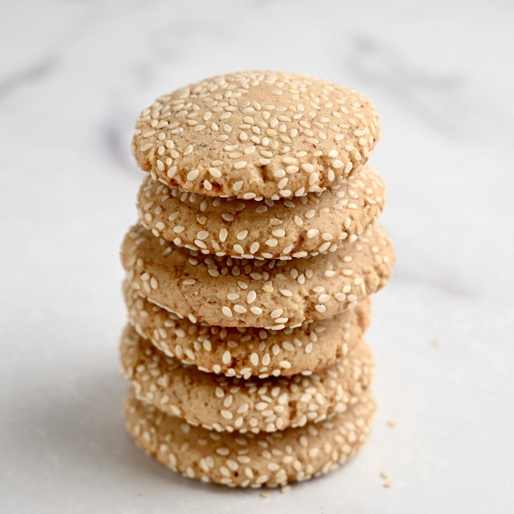 A stack of homemade sesame seed cookies on a marble countertop