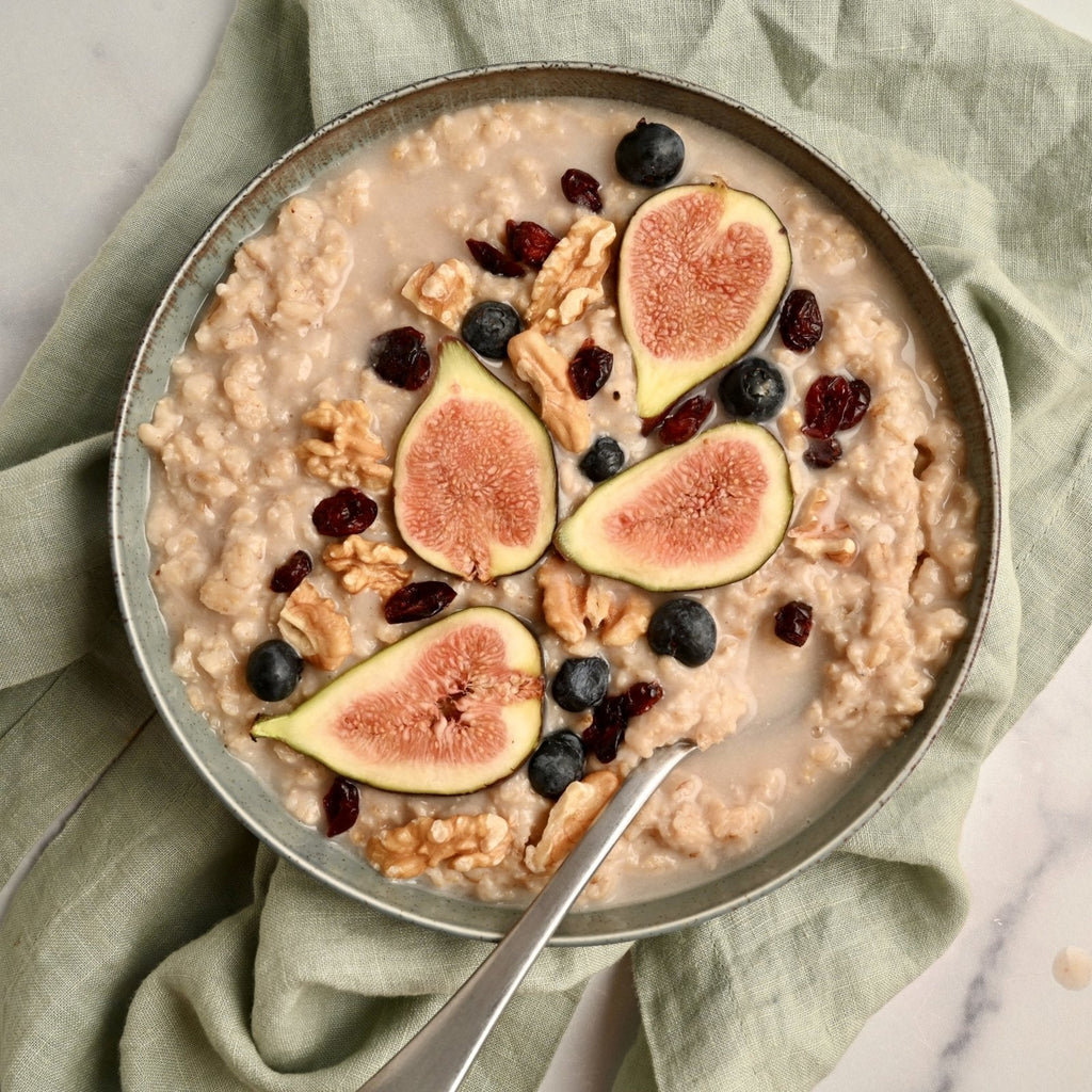 A bowl of oatmeal with fresh blueberries, figs, and walnut bits
