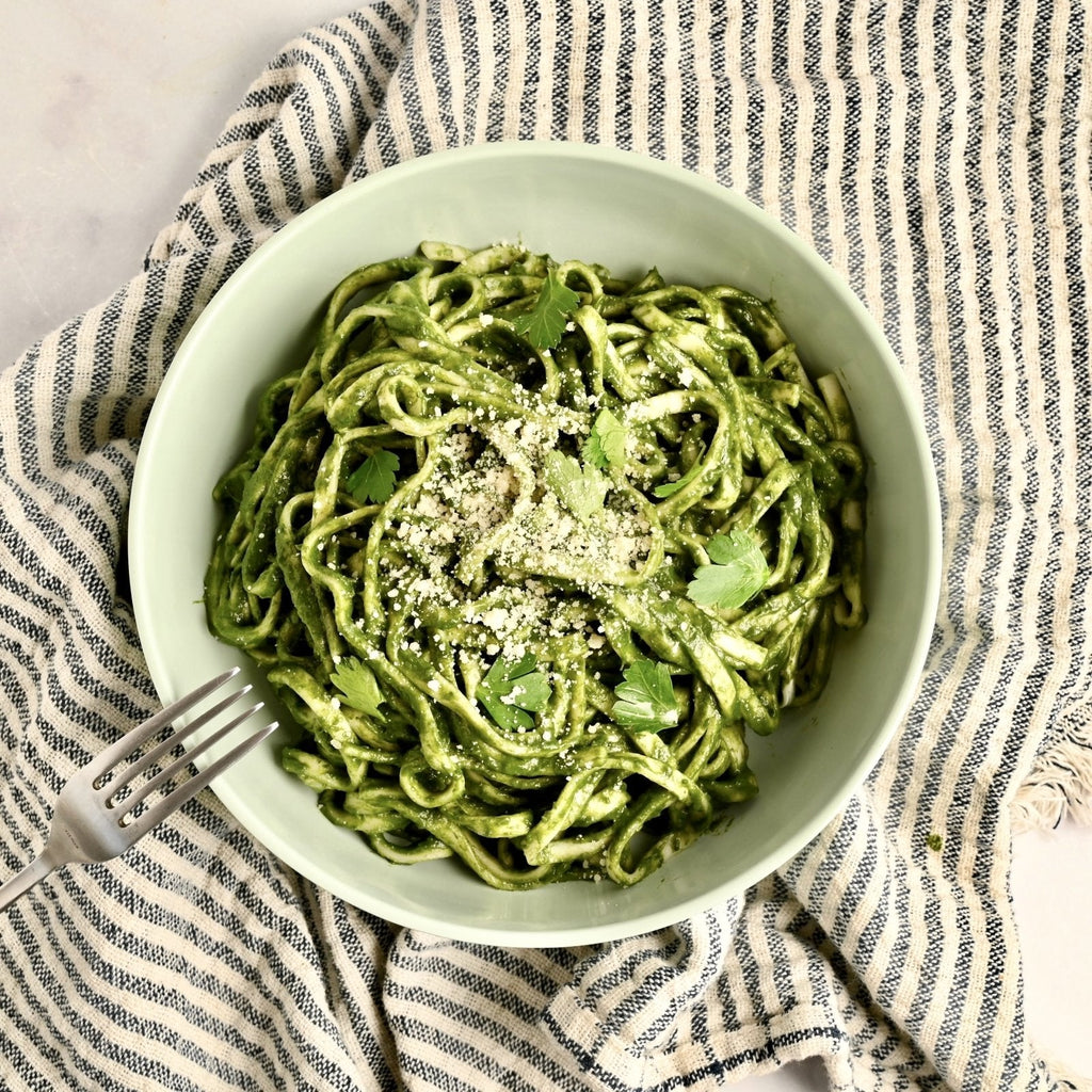 A bowl filled with pasta noodles and covered in spinach pasta sauce