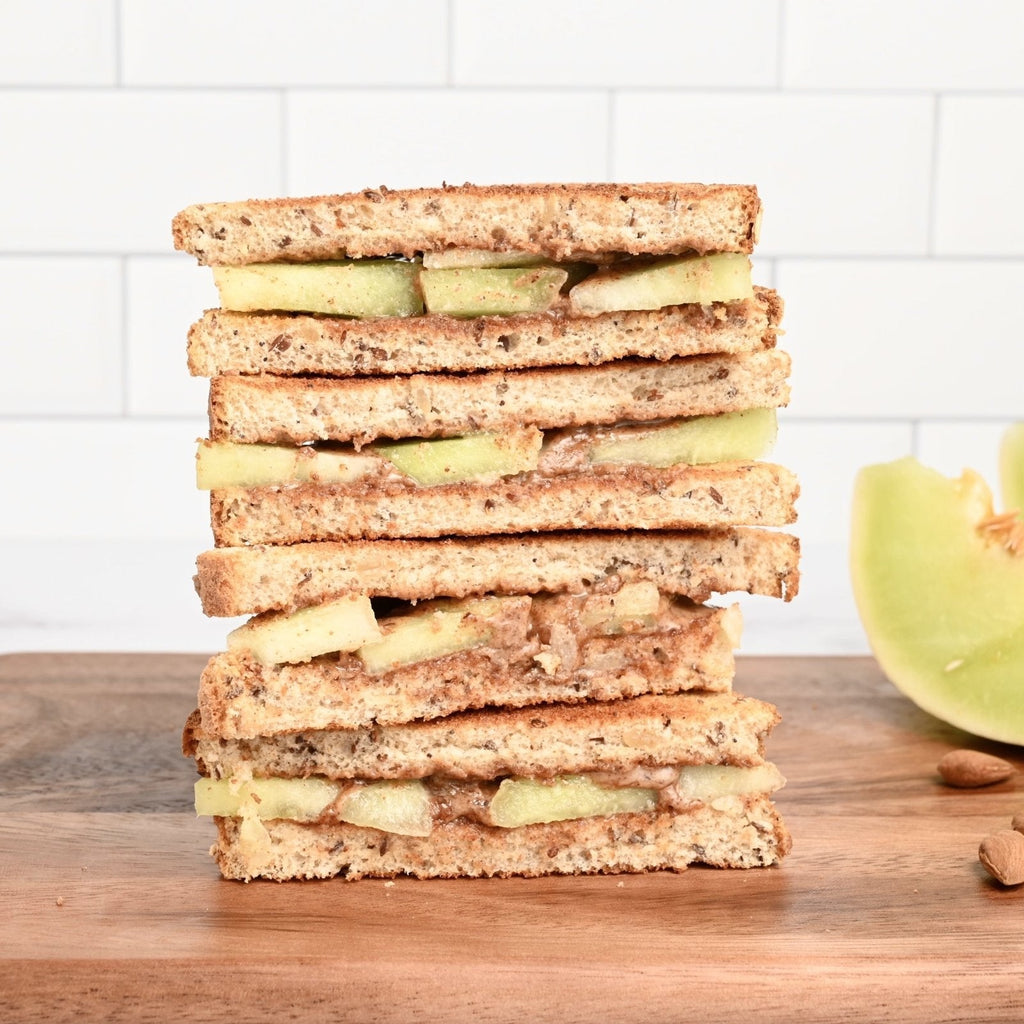 A stack of bread slices with almond butter and slices of honeydew melon