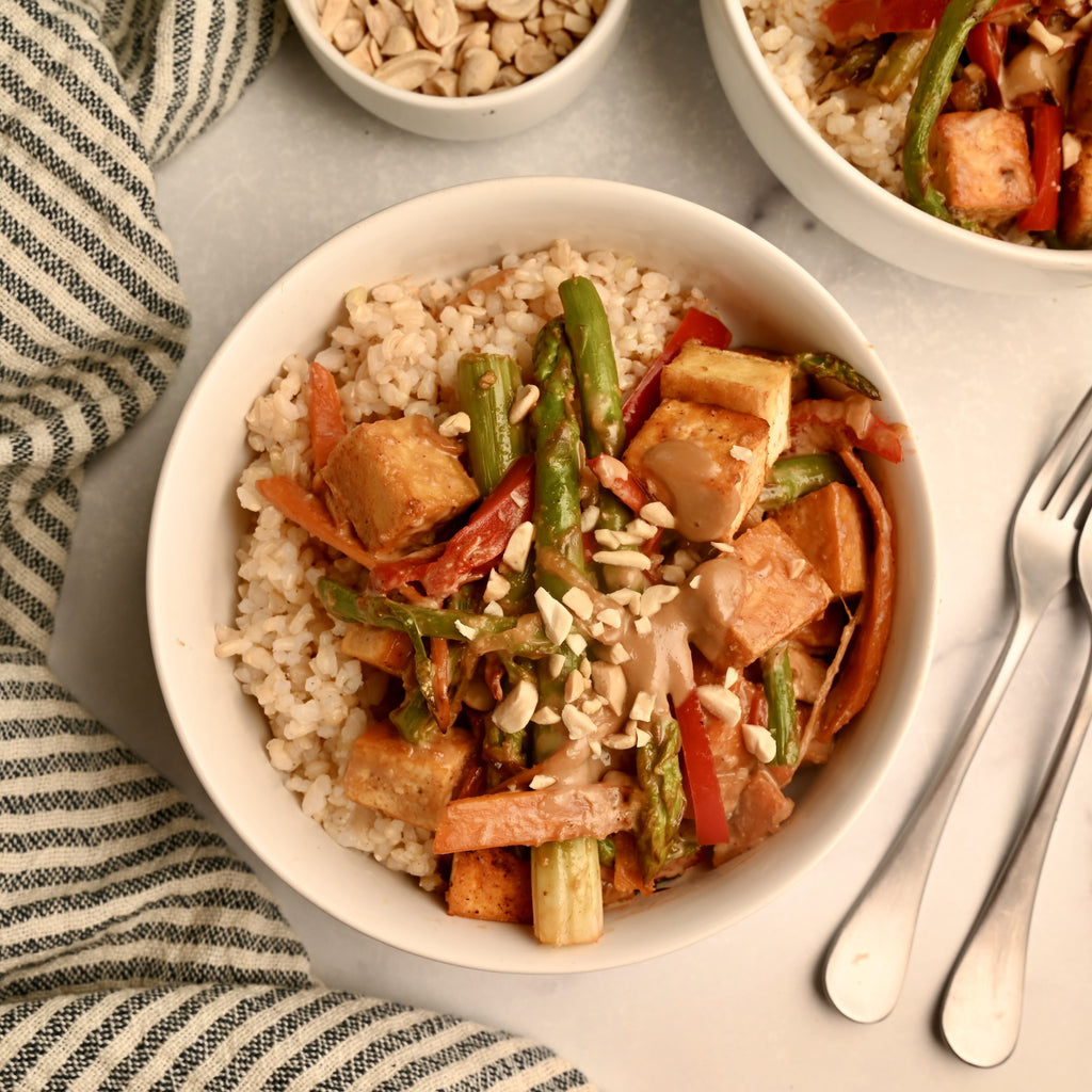 A white bowl filled with tofu and asparagus stir fry