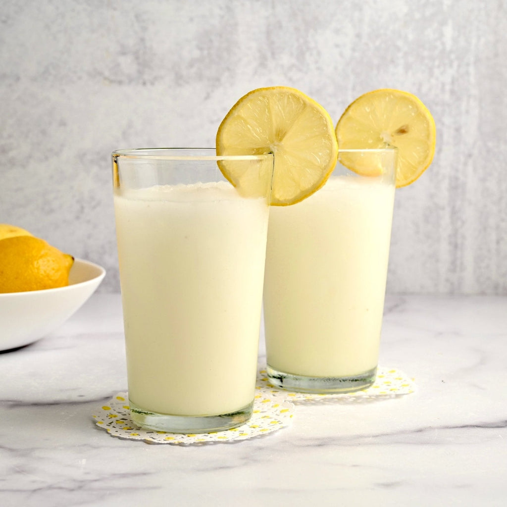 Two tall glasses filled with frozen lemonade with fresh lemon slices on each glass