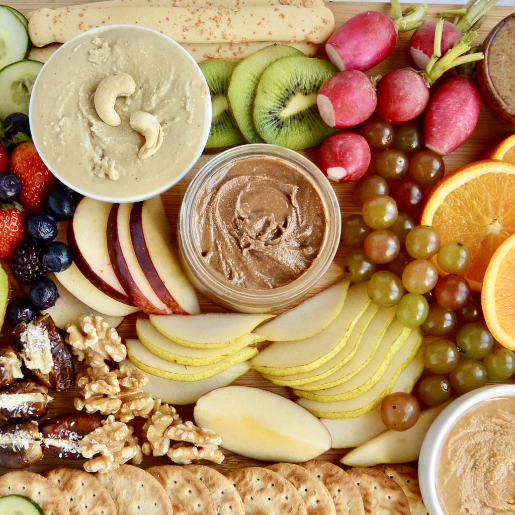Crackers, dips, and fruit on a charcuteria board