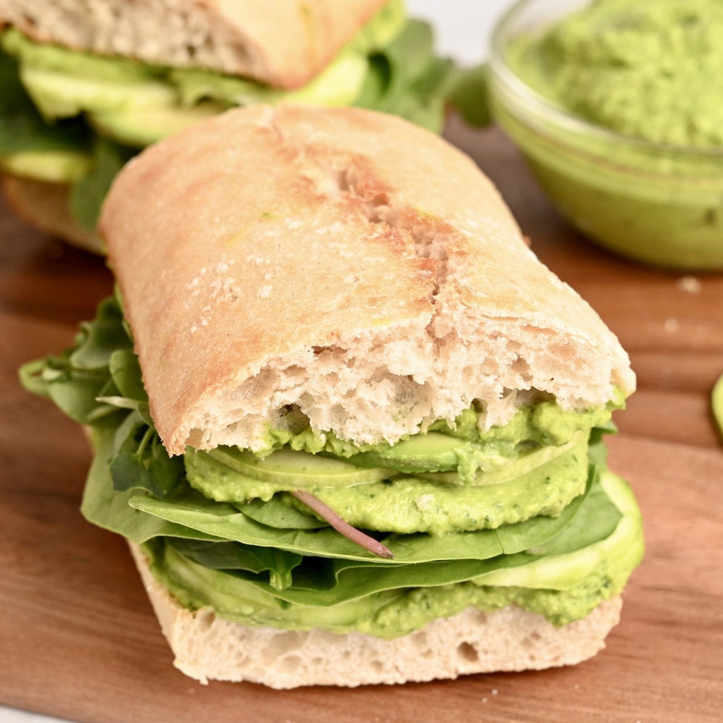 Baguette sandwich filled with leafy greens and avocado slices