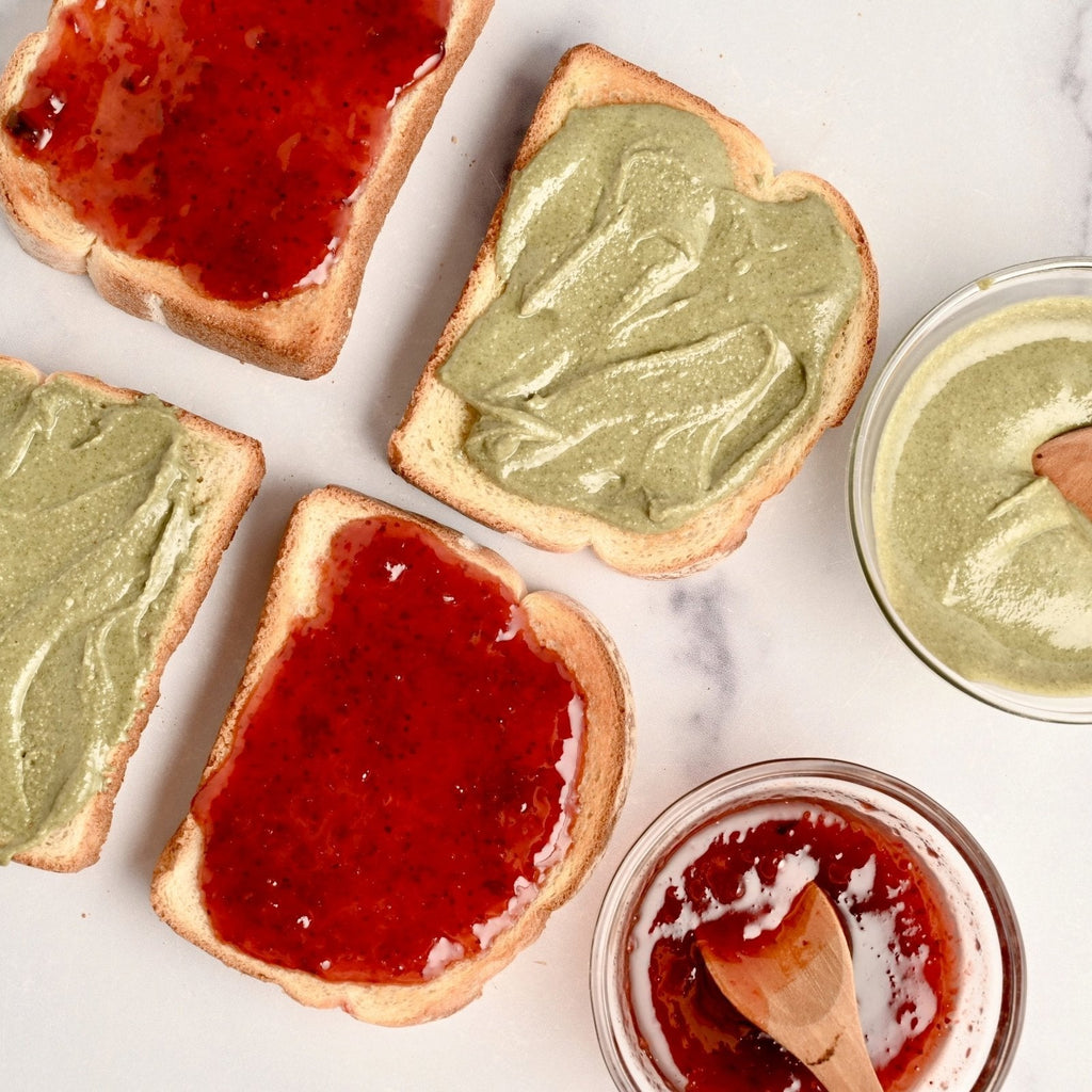 Slices of toast covered in green pumpkin seed butter and red jam