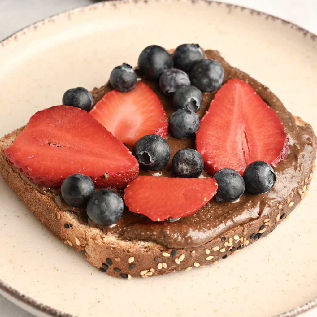 A slice of toast with a triple chocolate spread and fresh fruit on top including blueberries and sliced strawberries