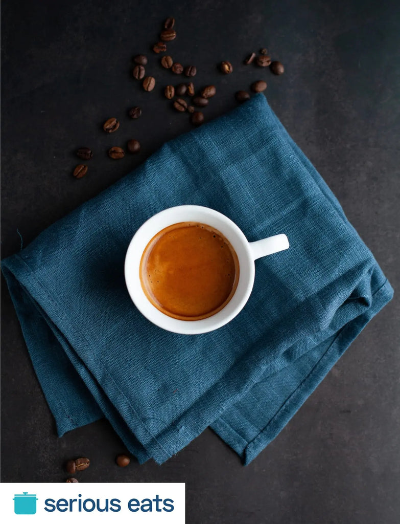 A cup of coffee sits on a blue napkin.
